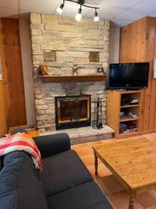 a living room with a couch and a stone fireplace at 2 bdrm Tremblant Haven-pets & spa-walk/ski to hill in Mont-Tremblant