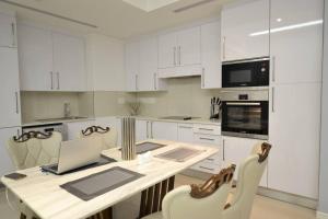a kitchen with white cabinets and a table with a laptop at Skyview Apartments in Gaborone