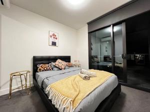 a bedroom with a large bed with a yellow blanket on it at Lovely 2 bedroom APT in centre of Olympic Park in Sydney