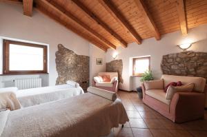 a bedroom with two beds and a couch and chairs at Rustico Bertel in San Zeno di Montagna