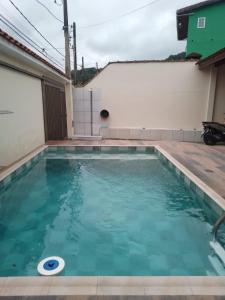 uma piscina numa casa com água azul em Casa espaçosa com Piscina e Churrasqueira 2 dorm no Guarujá