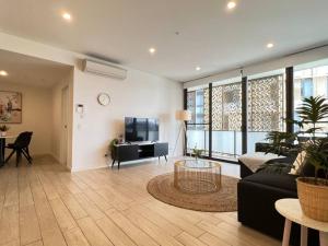 a living room with a black couch and a tv at Luxury 2 bedroom APT in Wentworth Point in Sydney