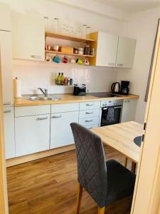 a kitchen with white cabinets and a wooden table at Ferienwohnung Edge-Inn 