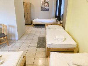 Habitación con 3 camas y suelo de baldosa. en Hotel Ava, en Gliwice