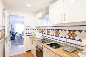 una cocina con armarios blancos y azulejos azules y blancos en OleHolidays Gala junto a Puente Romano en Marbella