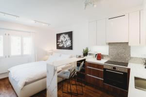 a white bedroom with a bed and a kitchen at Romantic JUMP Studio overlooking river, free parking in Ljubljana
