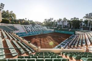 a tennis court with green seats on a tennis court at OleHolidays Gala junto a Puente Romano in Marbella