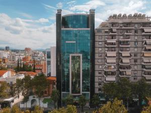 een hoog glazen gebouw in een stad met gebouwen bij Hotel Rosa Blu in Tirana