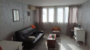 un soggiorno con divano in pelle nera e tavolo di Jela Apartman a Podgorica