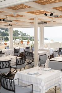 ein Restaurant mit weißen Tischen, Stühlen und Fenstern in der Unterkunft Hotel Canasta in Capri
