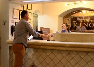 a man standing at a counter in front of a customer at Hotel Suites Kino in Hermosillo