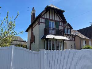 brązowy i biały dom za białym płotem w obiekcie Villa calme et spacieuse près de la plage, avec jardin et WIFI à Villers-sur-Mer - FR-1-712-53 w mieście Villers-sur-Mer