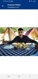 un uomo seduto a un tavolo con un piatto di pane di Bungalows Malagić a Gusinje