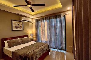 a bedroom with a bed with a ceiling fan and a window at Staycation at Sandari Batulao Overlooking Spot in Calo +94 photos