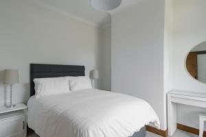 een witte slaapkamer met een wit bed en een spiegel bij Bar Cottage Number 2 in Altham