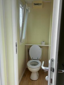 Elle comprend une petite salle de bains pourvue de toilettes et d'une fenêtre. dans l'établissement Camping Les Portes de la Baie de Somme, à Mareuil-Caubert