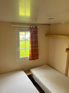 twee bedden in een kleine kamer met een raam bij Camping Les Portes de la Baie de Somme in Mareuil-Caubert