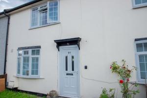 a white house with a white door and windows at Floral, 5 Bed House in London with Garden, Parking in Dagenham