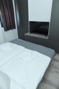 1 dormitorio con 1 cama blanca y TV en Apartman Maja 1 Crnjanski, en Jagodina
