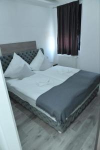 1 dormitorio con 1 cama grande con sábanas blancas y ventana en Apartman Maja 1 Crnjanski, en Jagodina
