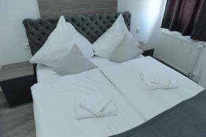 Una cama con sábanas blancas y almohadas. en Apartman Maja 1 Crnjanski, en Jagodina