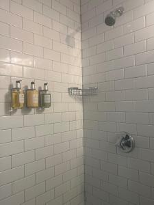 a white tiled shower with two bottles of soap at The Ellery Hotel in Provincetown