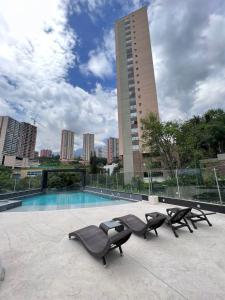 a pool with two lounge chairs and a building at Large Apartment High Views and Balcony in Medellín