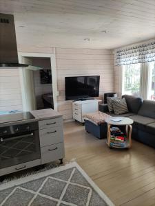 a living room with a couch and a tv at Kaukuanjärven Kimallus in Kuloharju