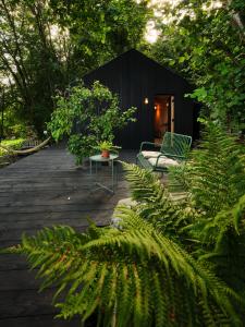 a black building with a table and a bench in a garden at Bay House Studio in Bath