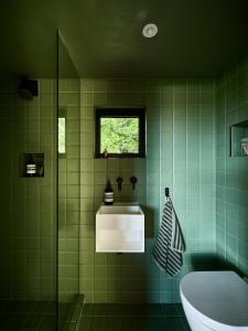 baño de azulejos verdes con bañera y lavamanos en Bay House Studio, en Bath