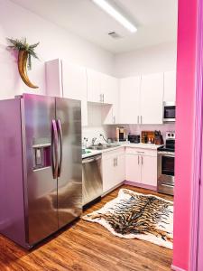 una cucina con frigorifero in acciaio inossidabile e pavimenti in legno di Dreaming With Dolly - Luxe Stay Near Broadway a Nashville