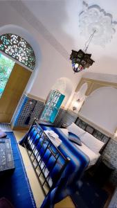 Schlafzimmer mit einem Bett mit blauer Bettwäsche und einem Kronleuchter in der Unterkunft Riad Al Nour in Marrakesch