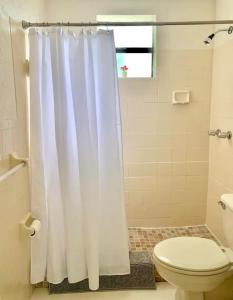 a bathroom with a white shower curtain and a toilet at Huge Private Room, near the Airport - Free parking - 02 in Miami
