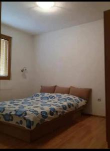 a bedroom with a bed with a blue and white comforter at Žabljak Apartman in Žabljak