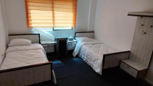 Zimmer mit 2 Betten, einem Schreibtisch und einem Fenster in der Unterkunft City Center Hostel in Gerasa