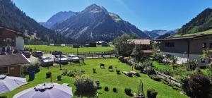 einen Garten mit Sonnenschirmen und einem Berg im Hintergrund in der Unterkunft Gästehaus Thaler in Mittelberg