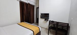 a small bedroom with a bed and a tv at BLUEWAY RESIDENCY DOWNTOWN HOTEL in Trivandrum