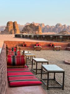 a room with tables and couches in the desert at Rum Under The Stars Camp in Wadi Rum