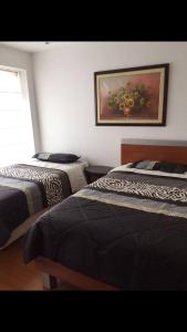 a bedroom with two beds and a painting on the wall at Urbanización El Condado. in Quito
