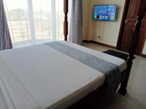 Ce lit se trouve dans un dortoir doté d'une télévision et d'une fenêtre. dans l'établissement Lovely 4 B/Rm Beachfront, à Mombasa