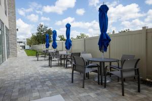 une rangée de tables et de chaises avec des parasols bleus dans l'établissement Holiday Inn Express & Suites Tampa Stadium - Airport Area, an IHG Hotel, à Tampa