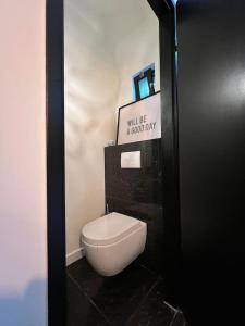 een wit toilet in een badkamer met een bord bij The coffee Corner Nuenen/Eindhoven in Nuenen