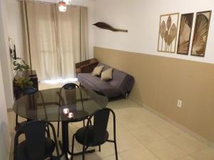 uma sala de estar com uma mesa de vidro e um sofá em Apartamento Canto do Forte na Praia Grande