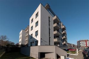 a tall white building in a parking lot at Sauna&Jacuzzi Apartment in Cluj-Napoca