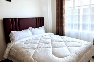 a bedroom with a white bed with a window at Faith homes near jkia in Nairobi