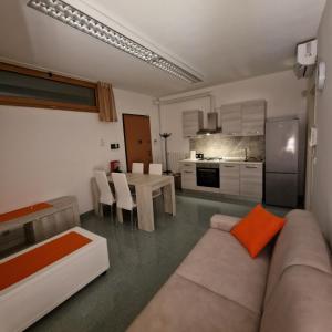 un soggiorno con divano e tavolo e una cucina di Attico al 4° ed ultimo piano con terrazzino e vista panoramica a Tricase