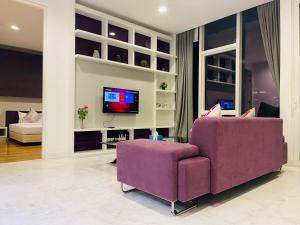 sala de estar con sofá púrpura y TV en The Platinum Suites KLCC By World Luxury, en Kuala Lumpur
