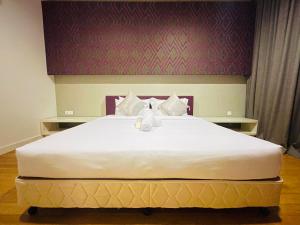 1 cama blanca grande en un dormitorio con pared morada en The Platinum Suites KLCC By World Luxury, en Kuala Lumpur