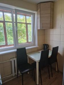 een keuken met een tafel en stoelen en 2 ramen bij Butas 34 in Šiauliai