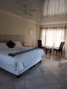 a bedroom with a bed and two chairs and curtains at 4 Seasons Country Club in Erasmus